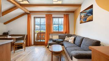 A cozy living room with a sofa, a small table, and a window with curtains.