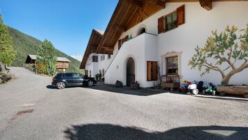 Un edificio con tetto spiovente, travi in legno e vialetto sterrato.