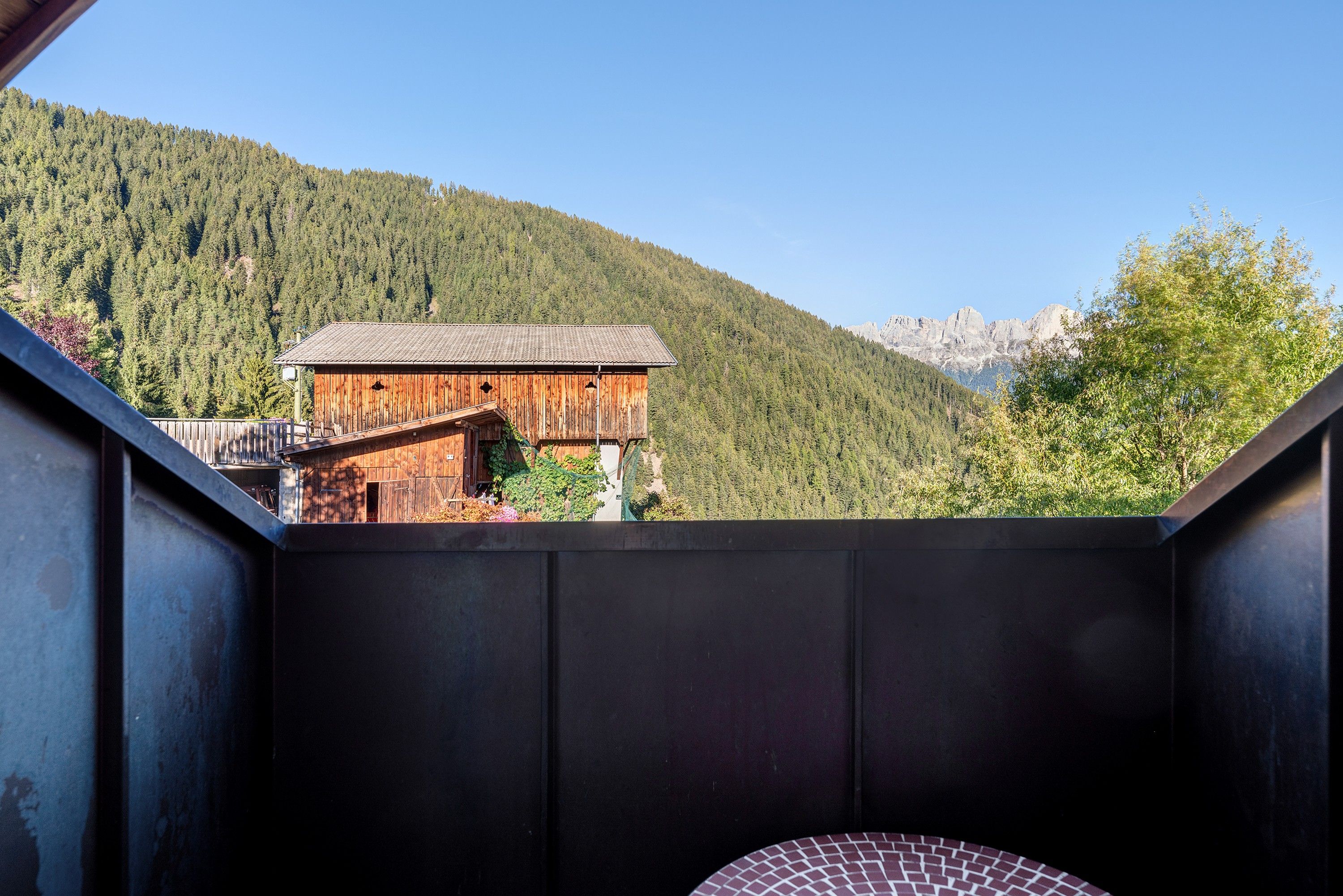 A room with a view of a wooden cabin and a mountain.