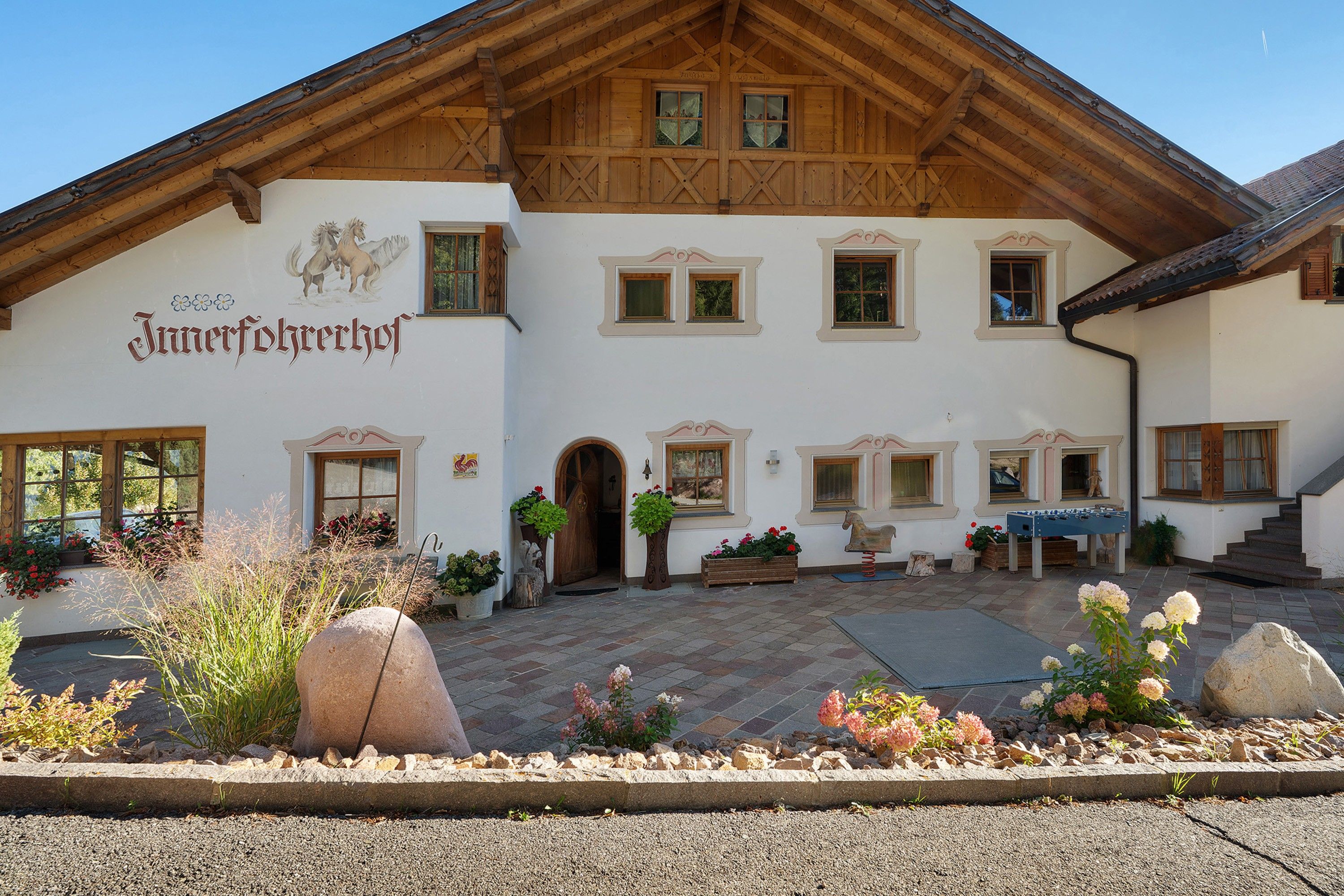 Ein traditionelles Gebäude im alpinen Stil mit Holzfassade, zahlreichen Fenstern und einem Schild, das es als 'Jungferhehrhof' kennzeichnet.