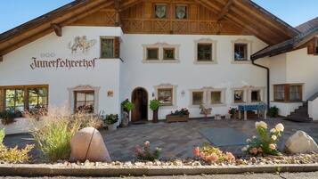 Ein traditionelles Gebäude im alpinen Stil mit Holzfassade, zahlreichen Fenstern und einem Schild, das es als 'Jungferhehrhof' kennzeichnet.