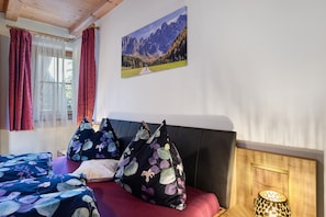Un dormitorio con cama, almohadas, un cuadro y una lámpara.