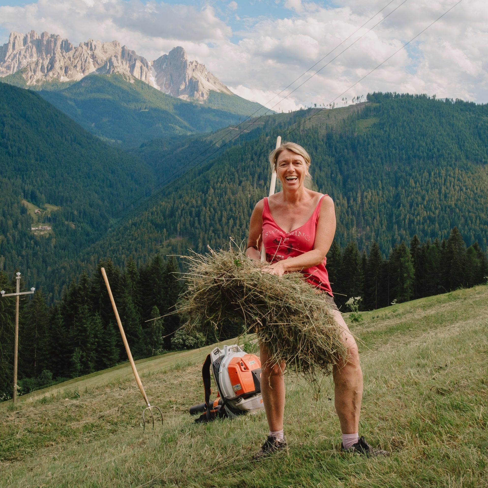 A person standing on a grassy hill with a mountain range in the background.