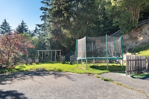 Un parque infantil con un trampolín, columpios y una estructura para escalar.