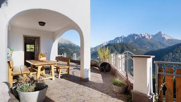 Une terrasse avec une table et des chaises, des plantes en pot et une vue sur les montagnes.
