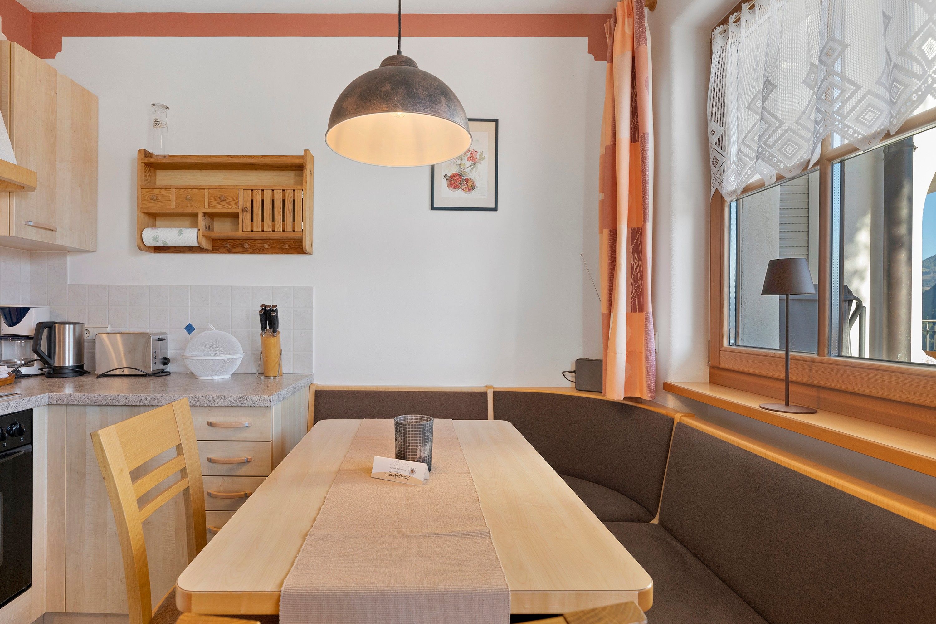 Een moderne keuken met houten kastjes, een ingebouwde bank en een eettafel.