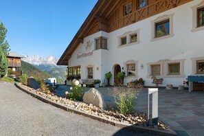 A traditional Alpine building with a mountain view, wooden beams, and a sign indicating a restaurant. - Apartment "3 Rosengarten" with Mountain View, Shared Garden and Wi-Fi (Nova Levante)
