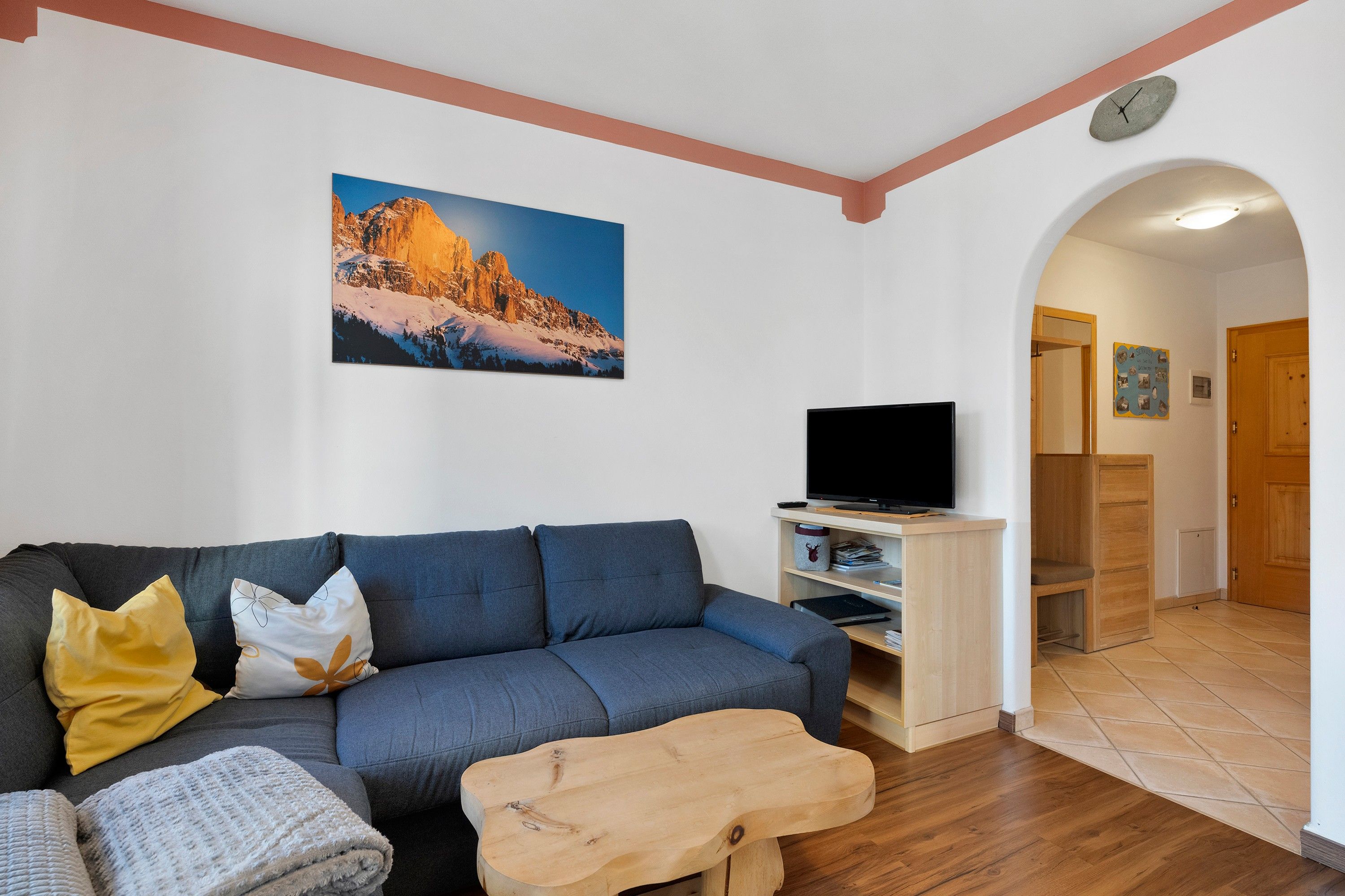 Una sala de estar con un sofá, un televisor y una mesa de centro de madera.