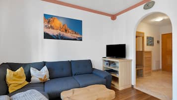 Una sala de estar con un sofá, un televisor y una mesa de centro de madera.