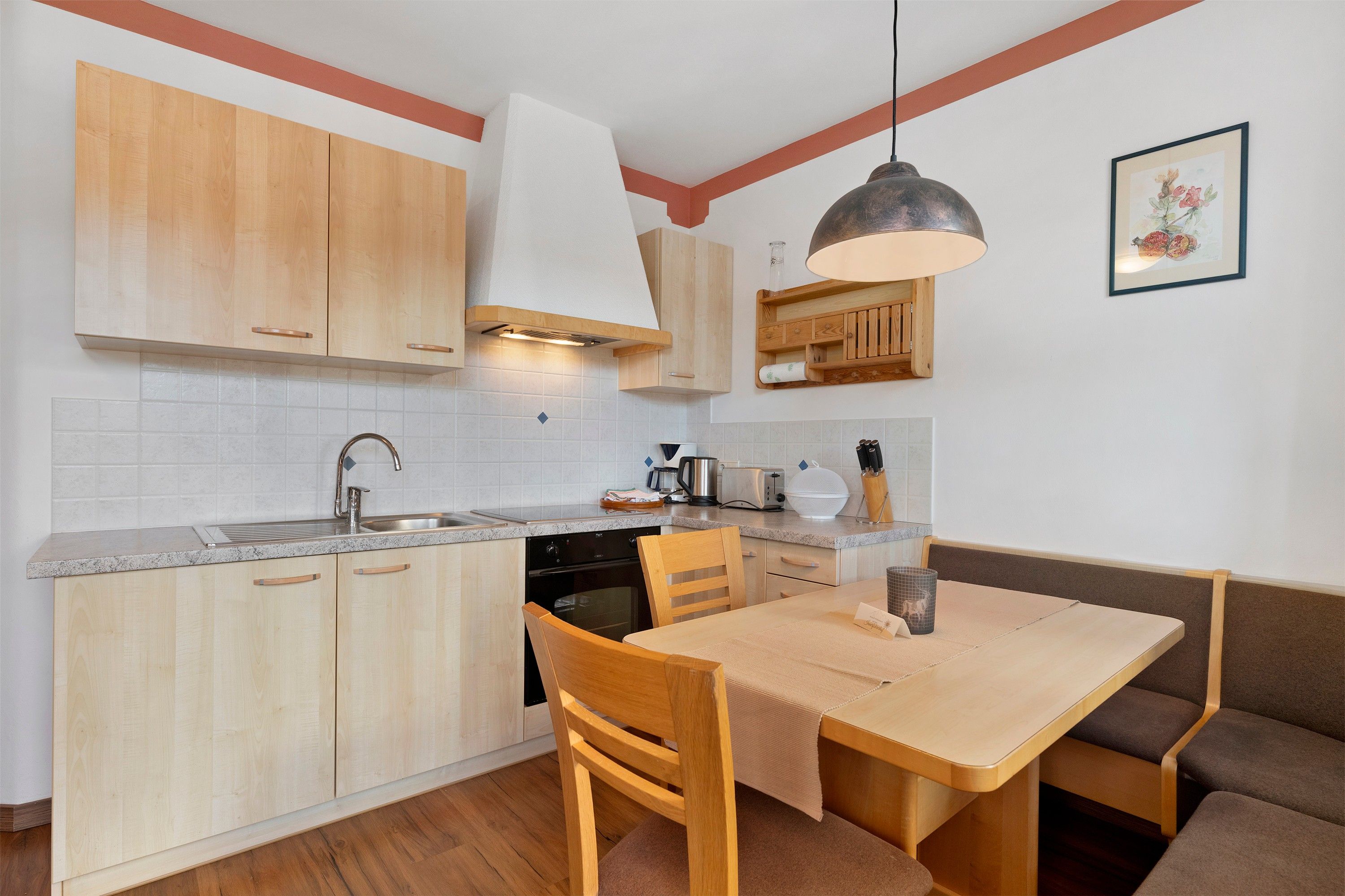 Une cuisine compacte avec des meubles en bois, un four encastré et un coin repas comprenant une table et des chaises.