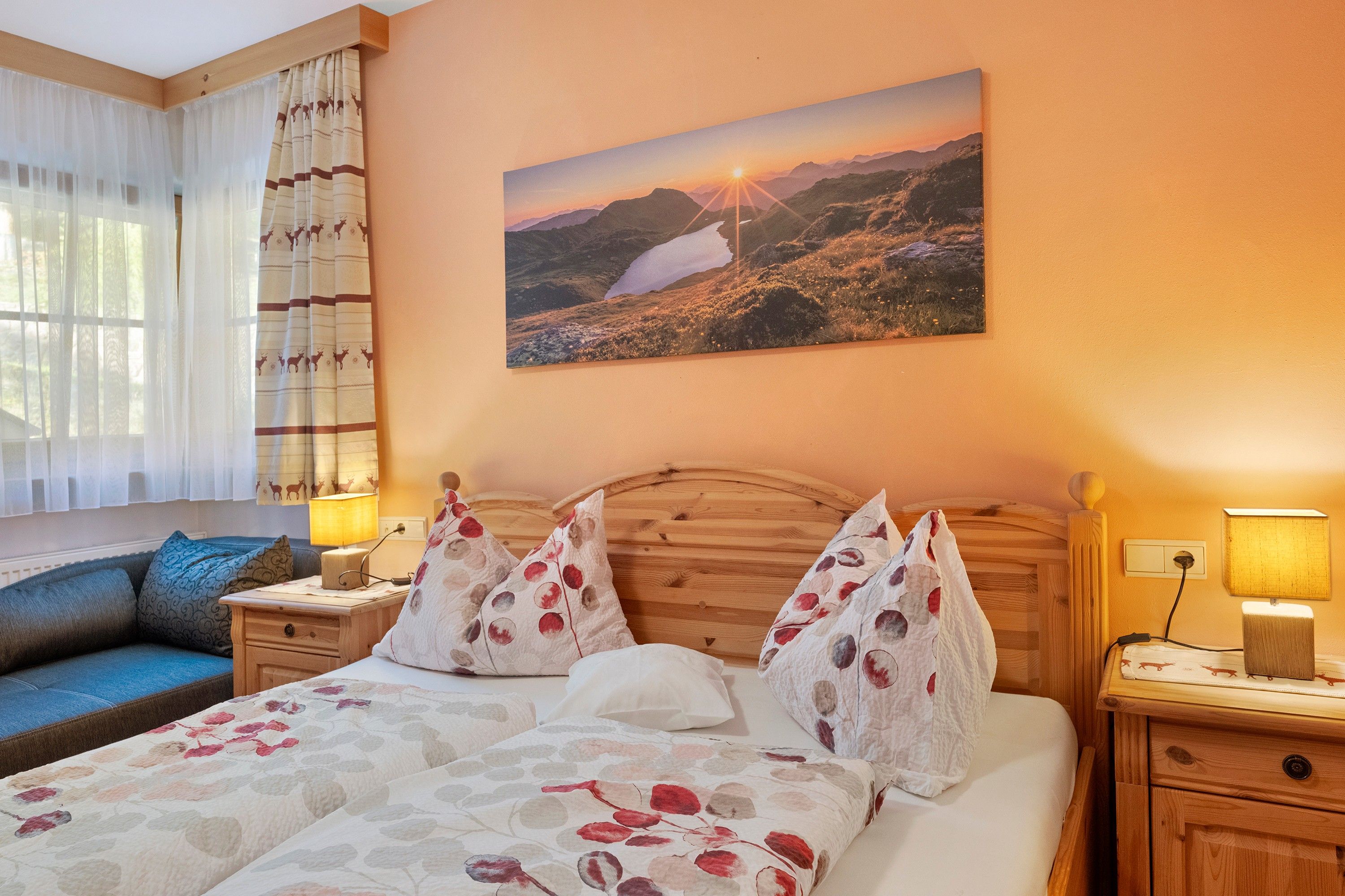 Une chambre d’hôtel avec un lit, une table de chevet, une lampe, une fenêtre avec des rideaux et un tableau au mur.