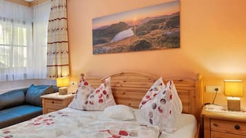 Une chambre d’hôtel avec un lit, une table de chevet, une lampe, une fenêtre avec des rideaux et un tableau au mur.