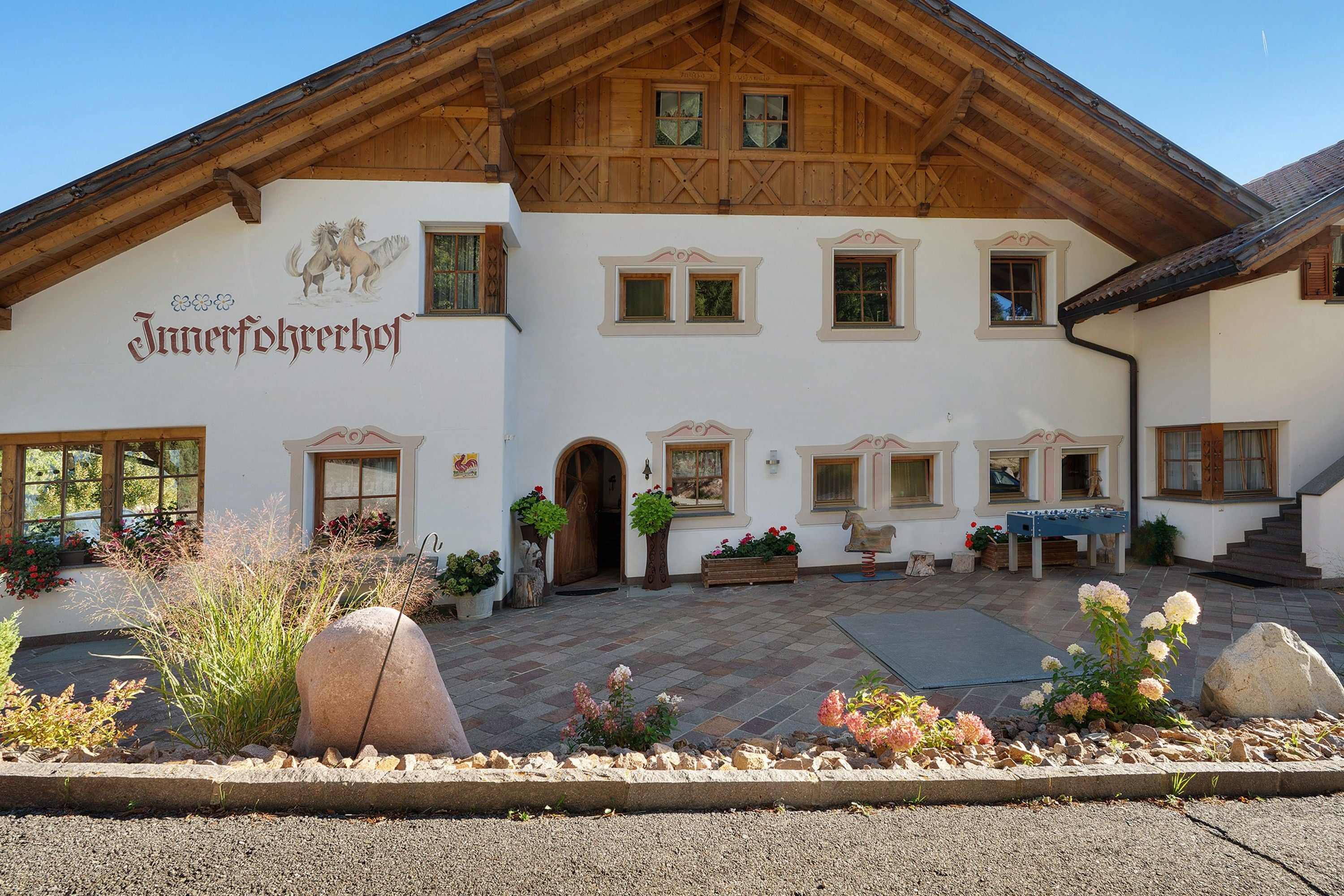 Il s’agit d’un bâtiment traditionnel de style alpin, doté d’une façade en bois, de nombreuses fenêtres et d’une enseigne indiquant qu’il s’agit d’un « Jungferhehrhof ».