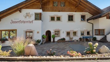 Il s’agit d’un bâtiment traditionnel de style alpin, doté d’une façade en bois, de nombreuses fenêtres et d’une enseigne indiquant qu’il s’agit d’un « Jungferhehrhof ».