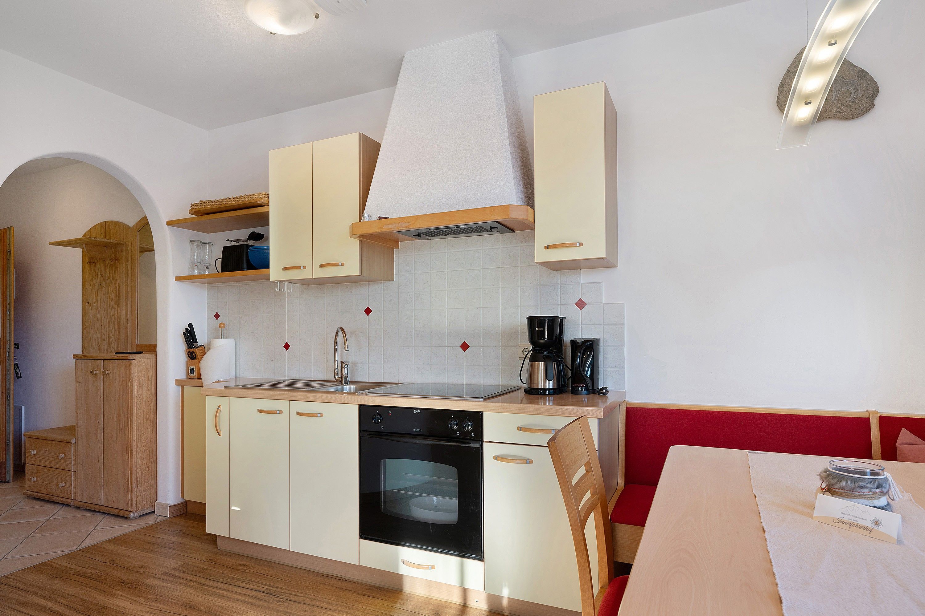 Una cucina compatta con mobili in legno, forno integrato e macchina da caffè.
