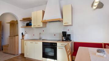 Una cucina compatta con mobili in legno, forno integrato e macchina da caffè.