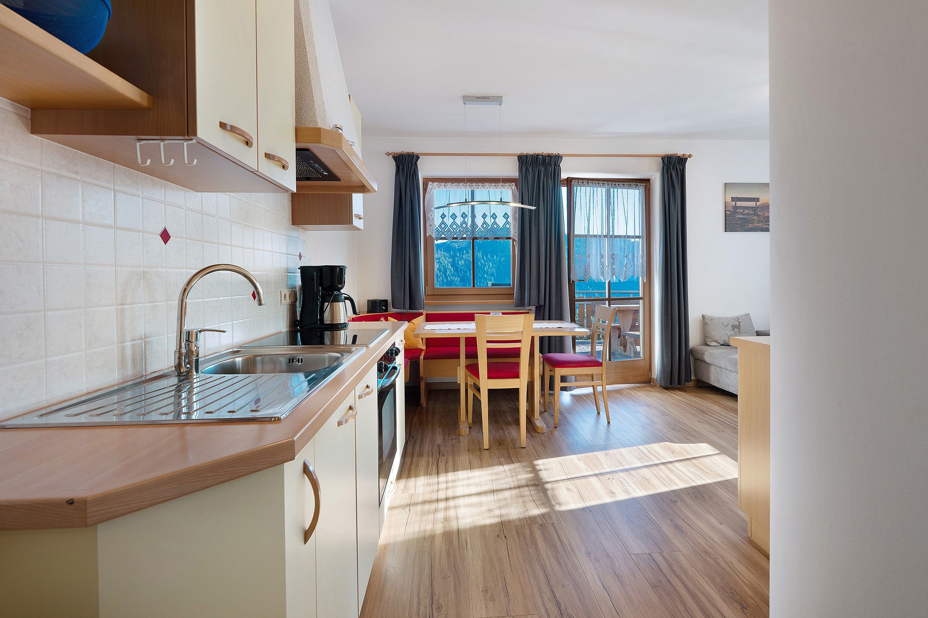 Une cuisine de taille réduite comprenant un évier, une cuisinière et un coin repas avec des chaises et une table.