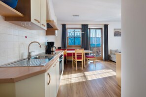 Cocina compacta con lavabo, estufa y zona de comedor con sillas y mesa.