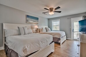 A bedroom with two beds, a ceiling fan, a window, and a television. - Summer Sun (Destin)