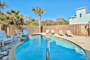 A swimming pool with a wooden fence, lounge chairs, and a palm tree. - Summer Sun (Destin)