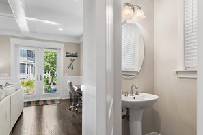 A bathroom with a white sink, a mirror, and a door leading to a patio. - Sea Esta (Santa Rosa Beach)