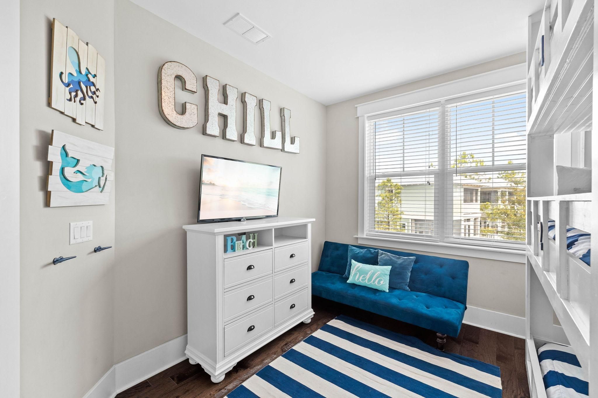 A room with a blue sofa, a white dresser, and artwork on the walls.