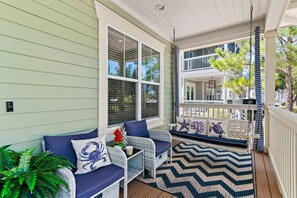 A covered porch with outdoor seating, a railing, and a view of the house. - Sea Esta (Santa Rosa Beach)