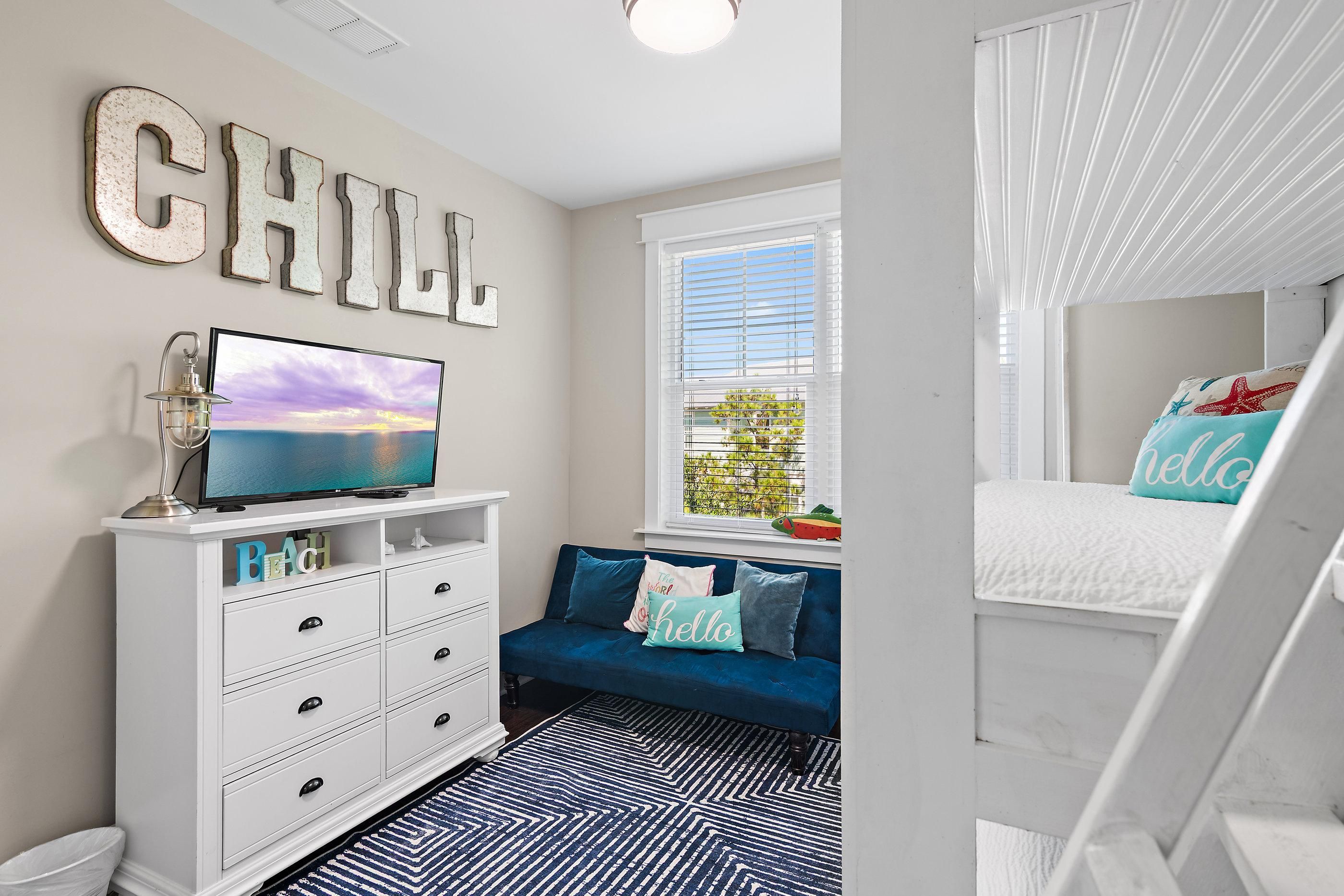 A bedroom with a bed, a TV, a dresser, and a window.