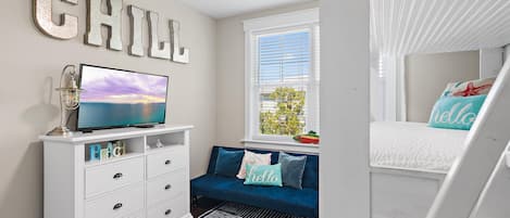 A bedroom with a bed, a TV, a dresser, and a window.