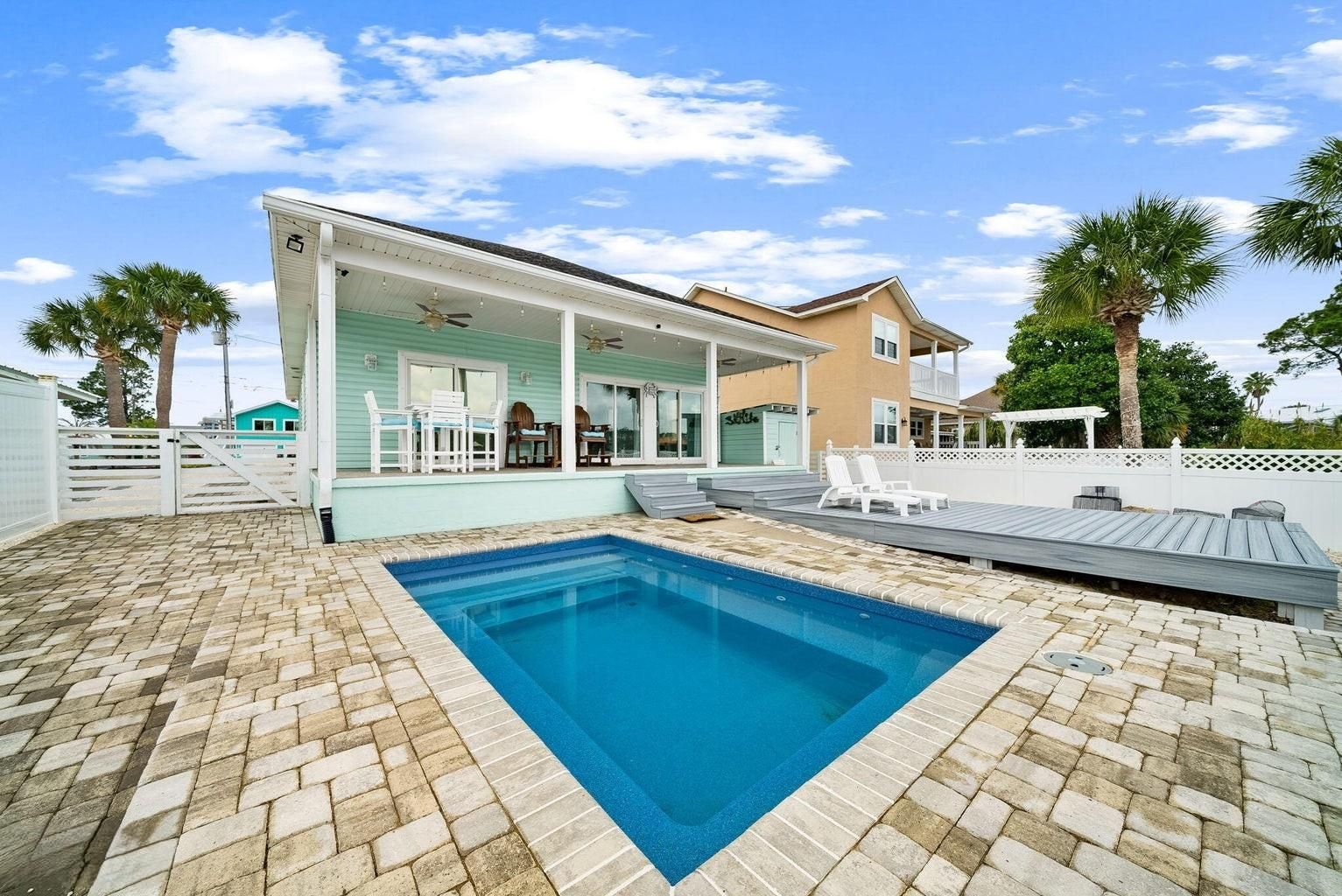 A residential property with a swimming pool, a covered patio, and a fenced backyard.