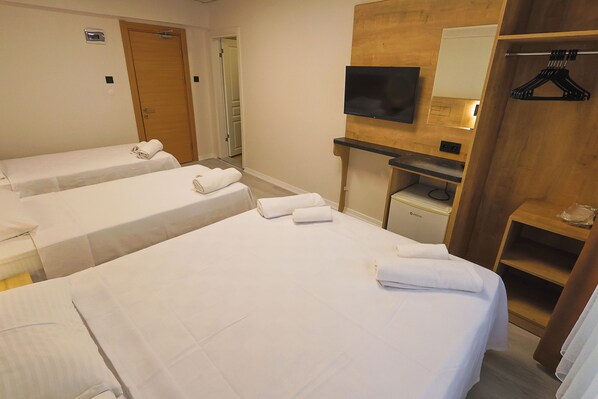 A hotel room with two single beds, a TV mounted on a wooden panel, and a wooden wardrobe with a mirror.