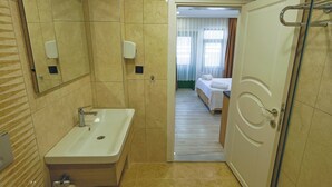 A hotel bathroom with a sink, mirror, and a shower area. - Doruk Pansiyon (Amasra)