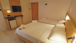 A hotel room with a large bed, a smaller bed, a TV, a desk, and a wooden cabinet. - Doruk Pansiyon (Amasra)