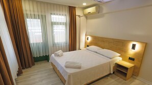 A hotel room with a bed, a bedside table, an air conditioning unit, and a window with curtains. - Doruk Pansiyon (Amasra)