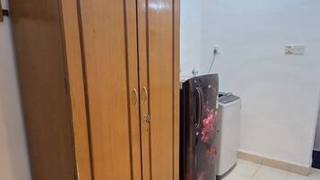 Ein Zimmer mit einem Holzschrank, einer Mülleimer und einem Kühlschrank.