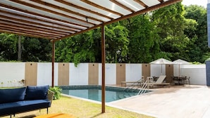 A covered outdoor area with a pool, seating, and a pergola structure. - BNB Flex Premium (Recife)