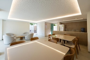 A modern interior with a dining area, seating, and a kitchen. - BNB Flex Premium (Recife)
