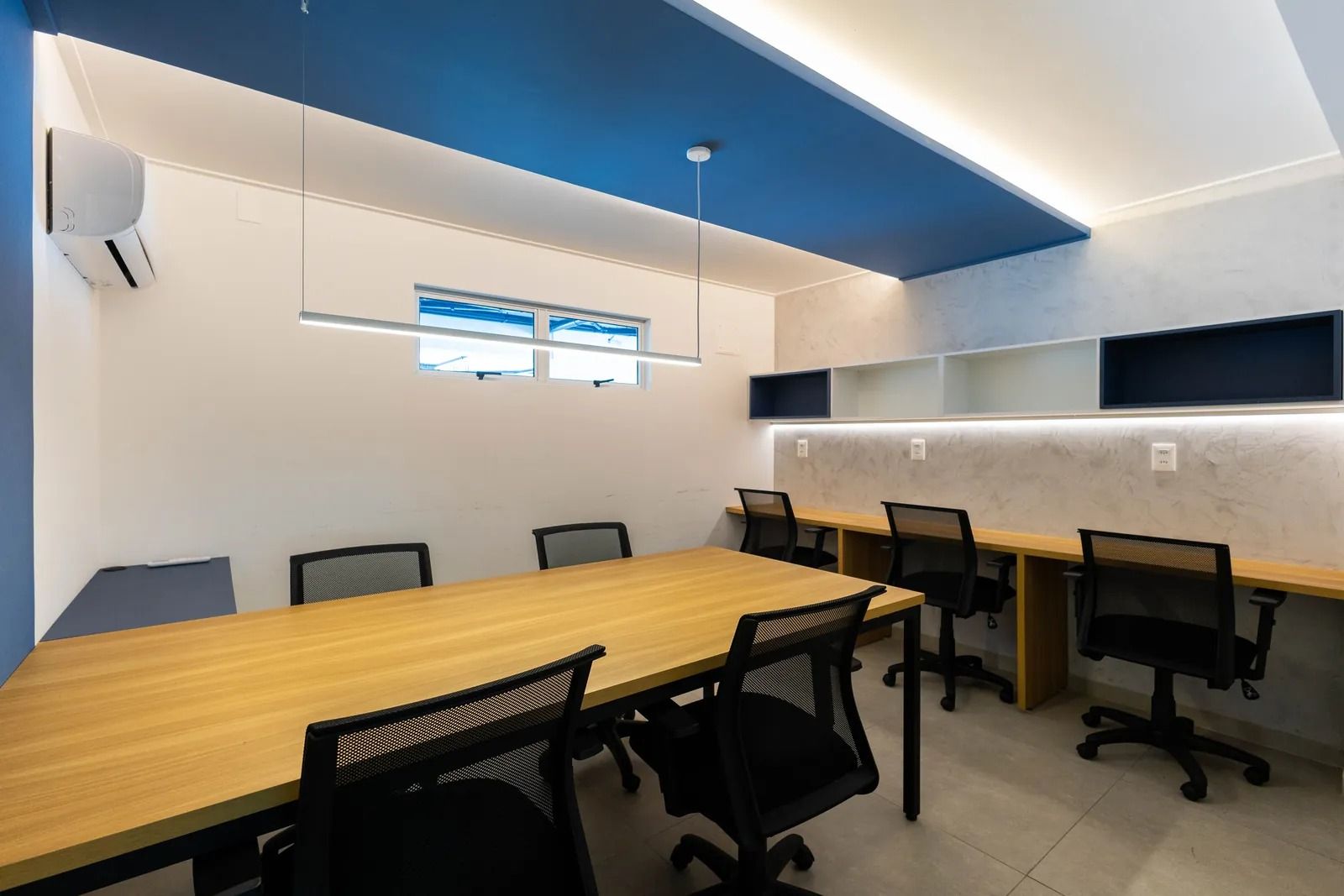 A conference room with a long table, six chairs, and a ceiling with blue and white sections.