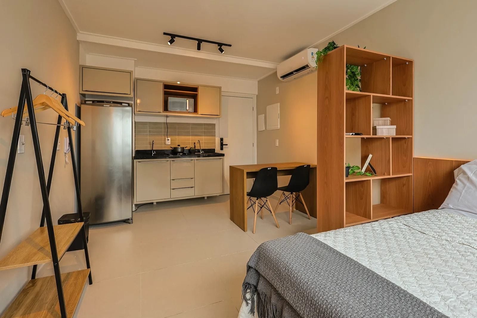 A compact studio apartment with a kitchenette, a bed, a desk, and a wardrobe.