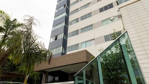 A high-rise building with a modern architectural design, featuring a glass entrance and a staircase leading to the upper floors. - BNB Flex Premium (Recife)