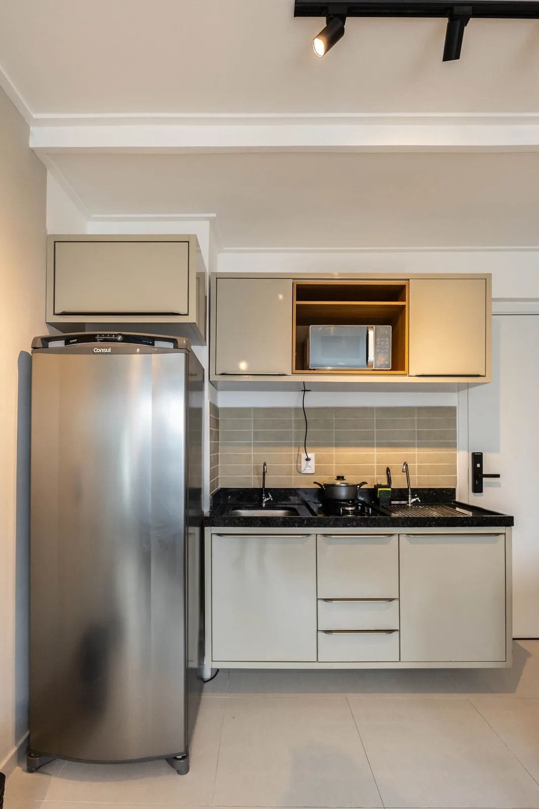 Una cocina moderna con un refrigerador de acero inoxidable, un microondas y una estufa a gas.