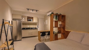 A compact bedroom with a bed, a desk, and a kitchenette. - BNB Flex Premium (Recife)