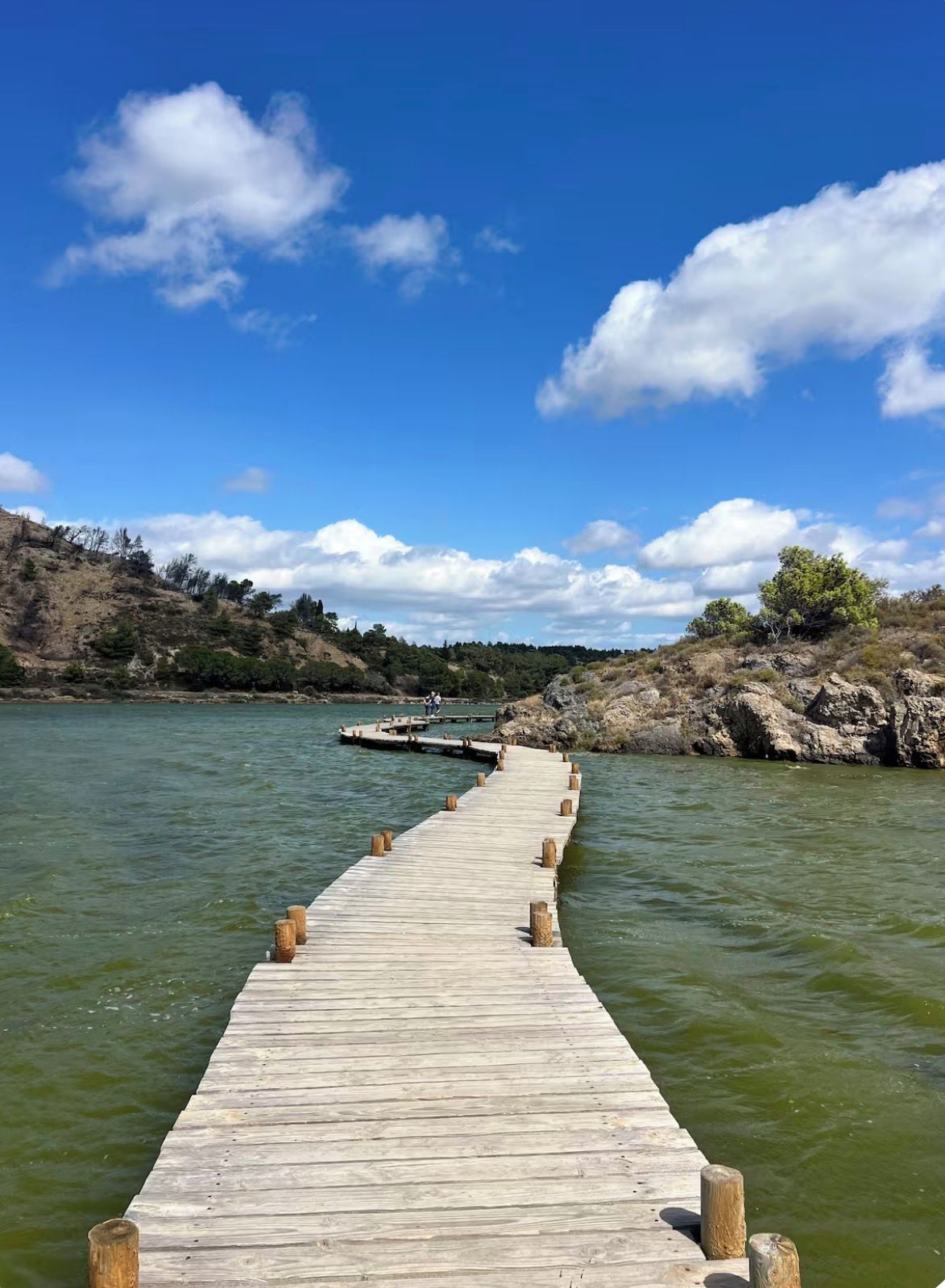 A wooden pier extending into a body of water, with a clear sky above.
