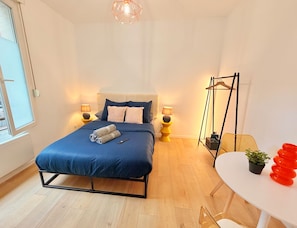 A modern bedroom with a bed, bedside lamps, a hanging light fixture, a small table with a plant, and a chair. - Le BARN -> a stylish urban retreat ❤️ (Le Havre)