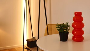 A room with a white table, a black hanging chair, a small potted plant, and a red vase. - Le BARN -> a stylish urban retreat ❤️ (Le Havre)