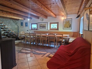 A cozy room with a wooden staircase, a dining table with chairs, a bench, and a red bean bag.