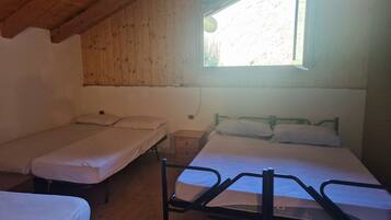 A room with two single beds and a larger bed, wooden walls, a window with a view, and a wooden ceiling.