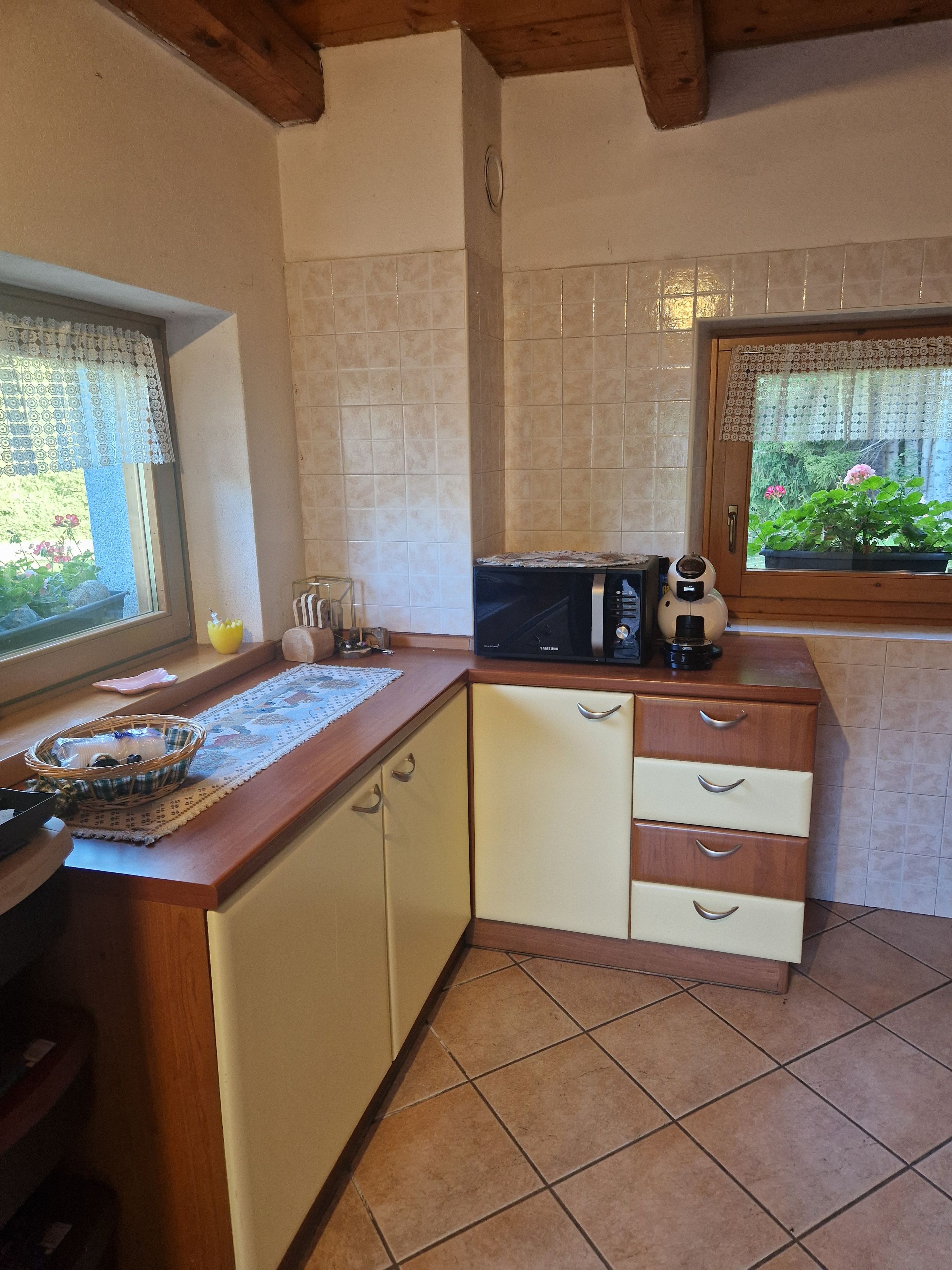 A compact kitchen with a microwave, a sink, and a window with a view of greenery.