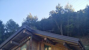 Kivinen rakennus, jossa on puinen penkki, puiset ovet ja ikkuna, jossa on vihreä verho.
