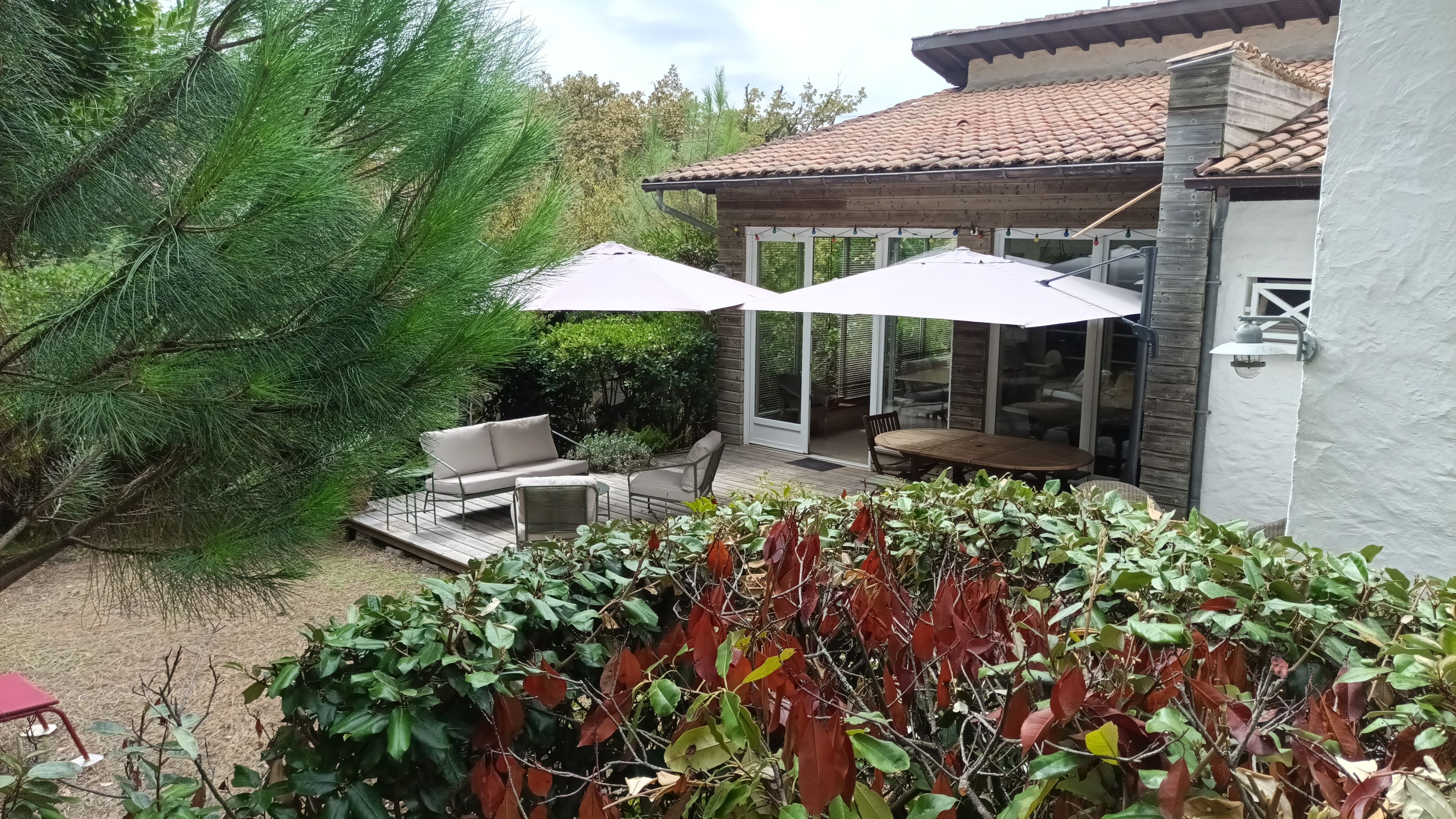 Un patio con mobiliario exterior, una pérgola y vista de la casa.